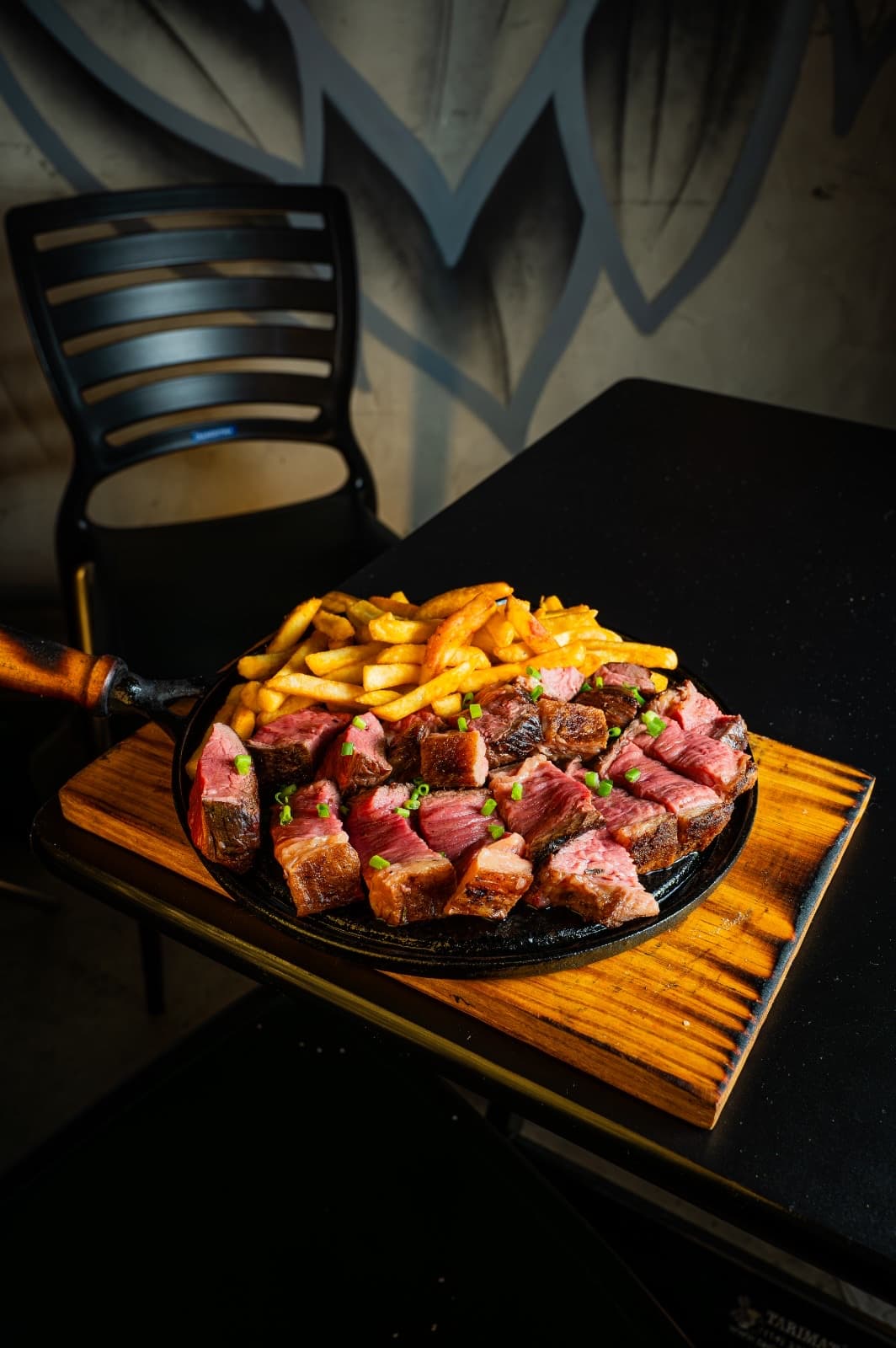 Corte de carne na brasa com batatas fritas servido na chapa do Chama Burger & Steak